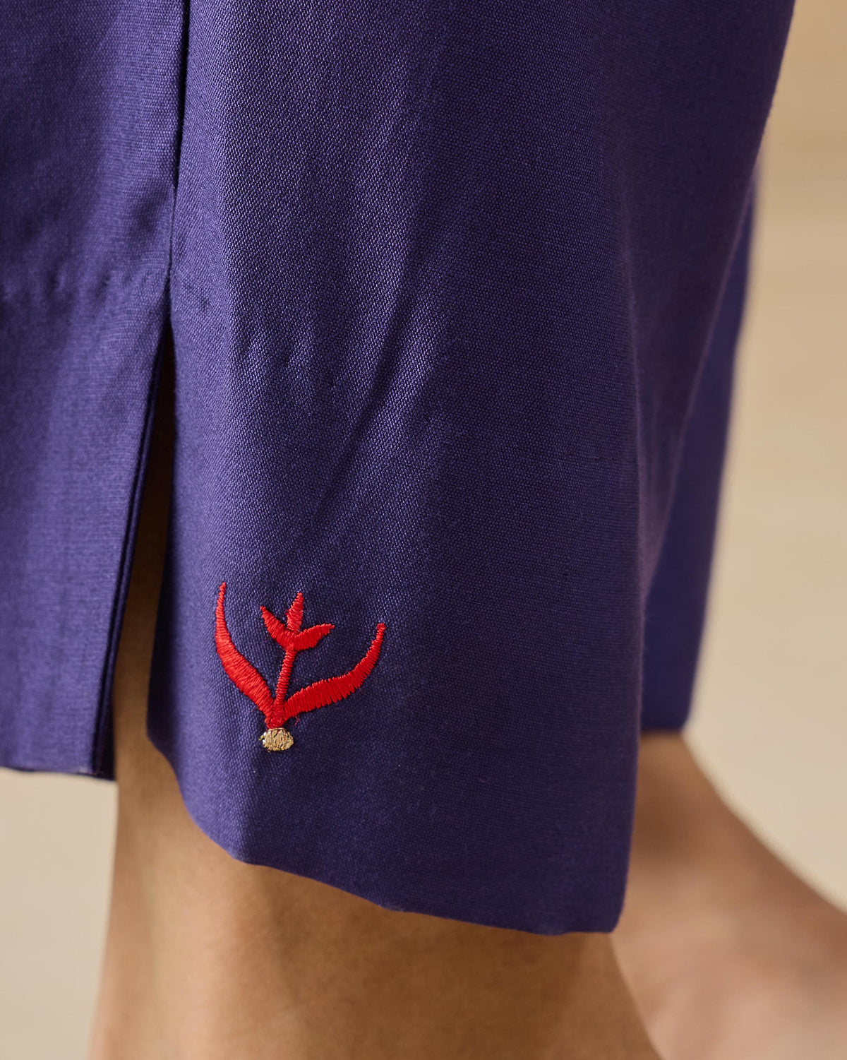 Close-up of purple Darjeeling pants hem with a red embroidered motif.