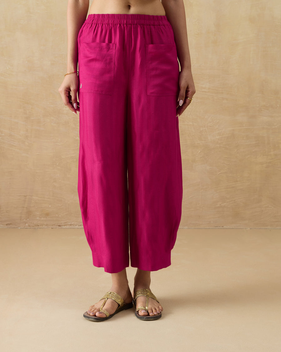 The Serene Pants, relaxed-fit berry silk blend pants with front pockets, worn with flat sandals.