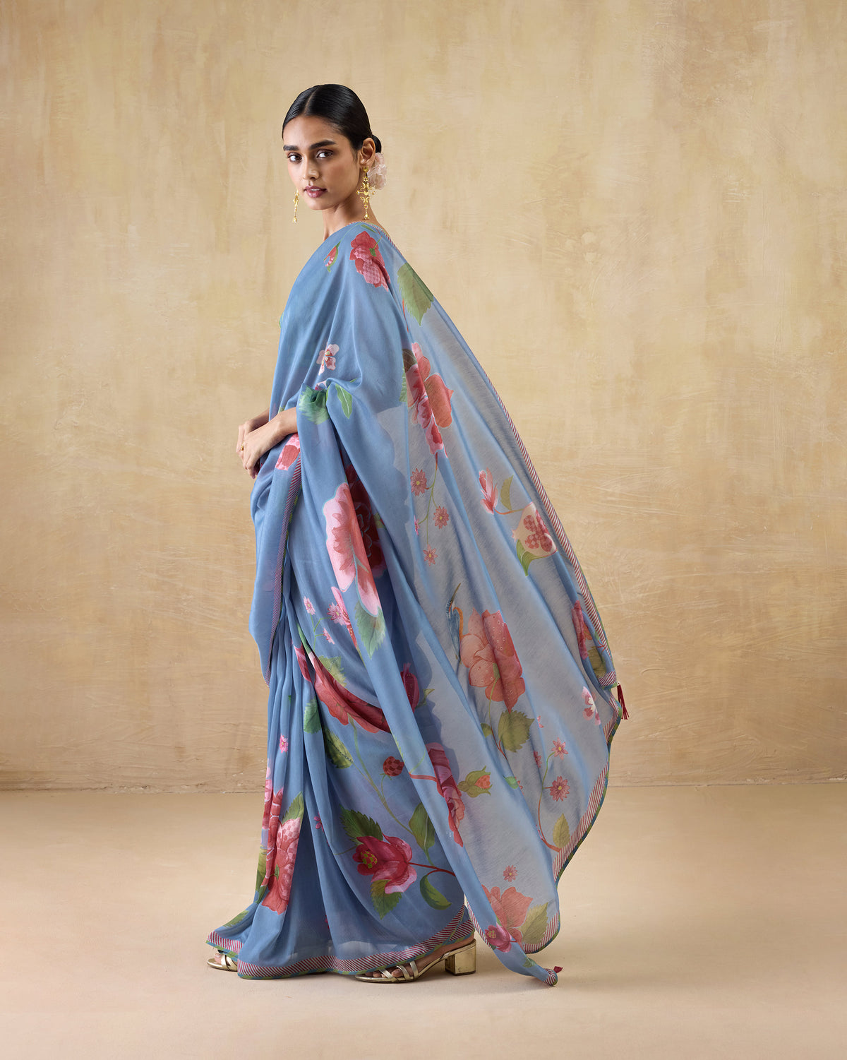 Side view of a blue First Bloom sari with a pink rose print worn by a person.