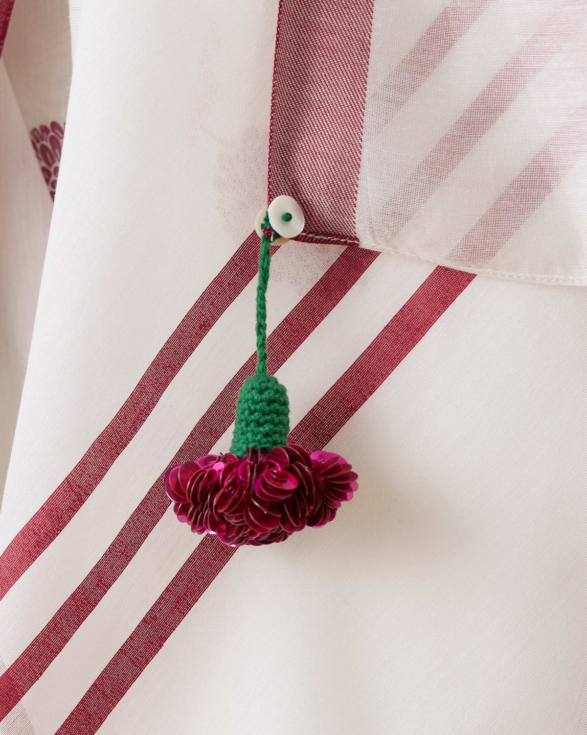 Close-up of a sequined floral tassel on the red-striped ivory Stardust sari pallu.
