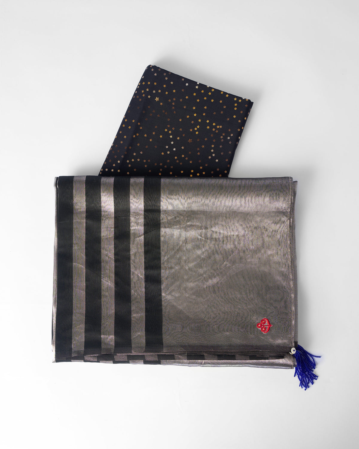 Folded silver Party Stripes sari with black stripes, blue tassel, and a navy blouse piece.