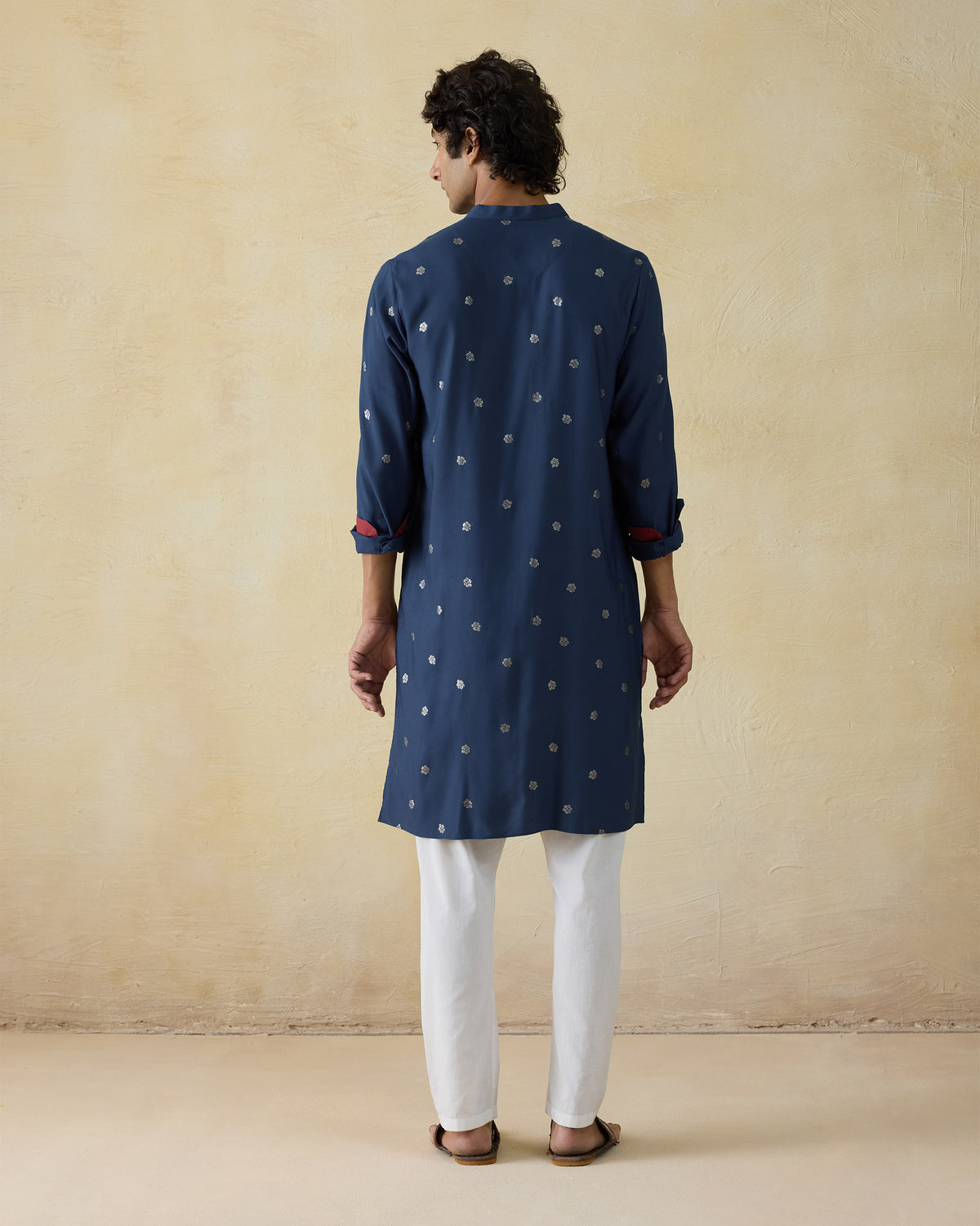 Back of a dark blue astral kurta with silver autumn bloom motifs worn by a person.