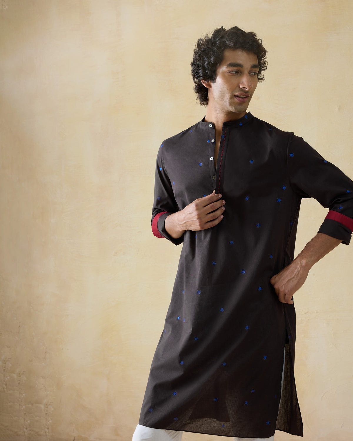Person wearing a brown Gala Kurta with red cuff lining.