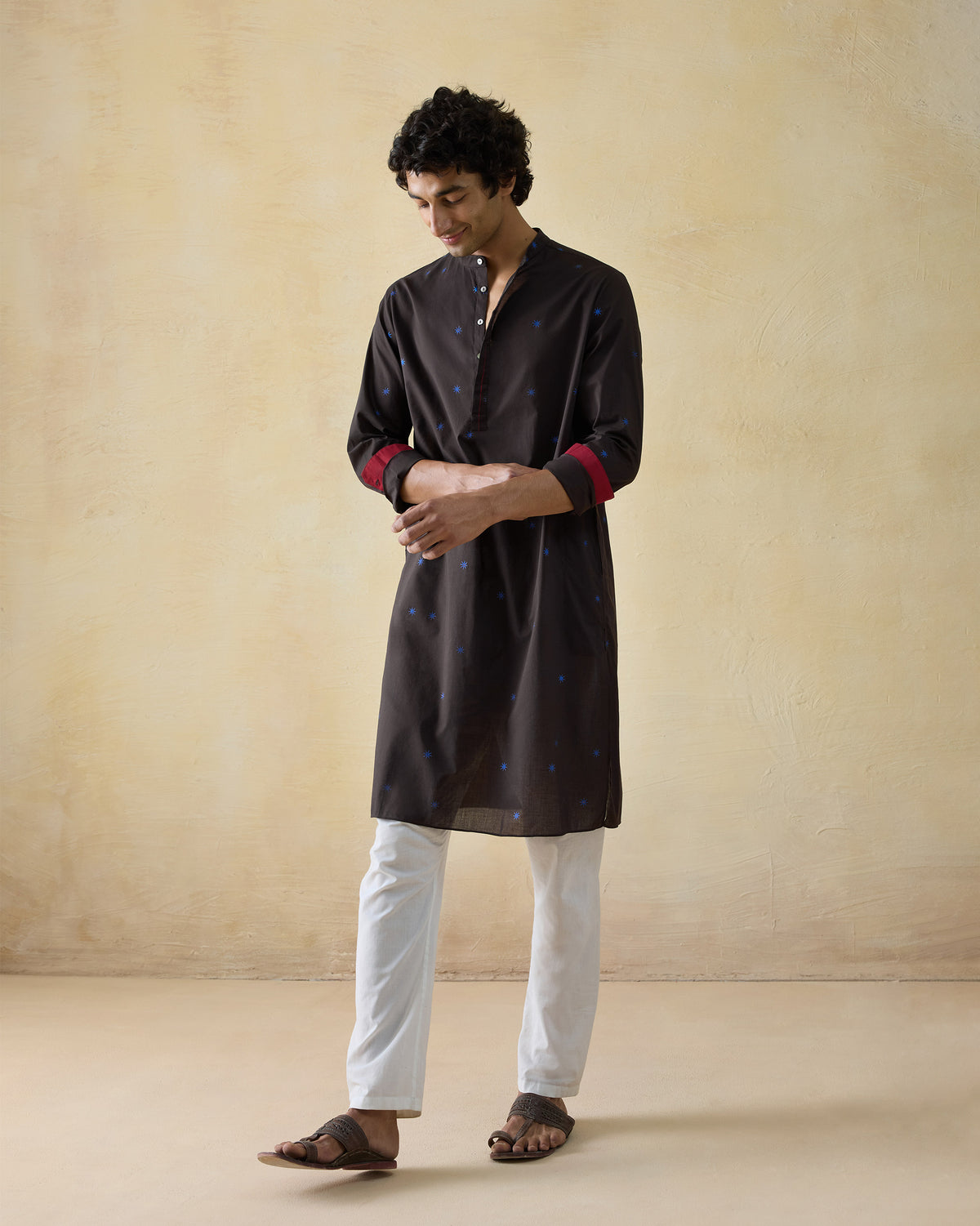 Person wearing a brown Gala Kurta with blue star dots and red cuffs.