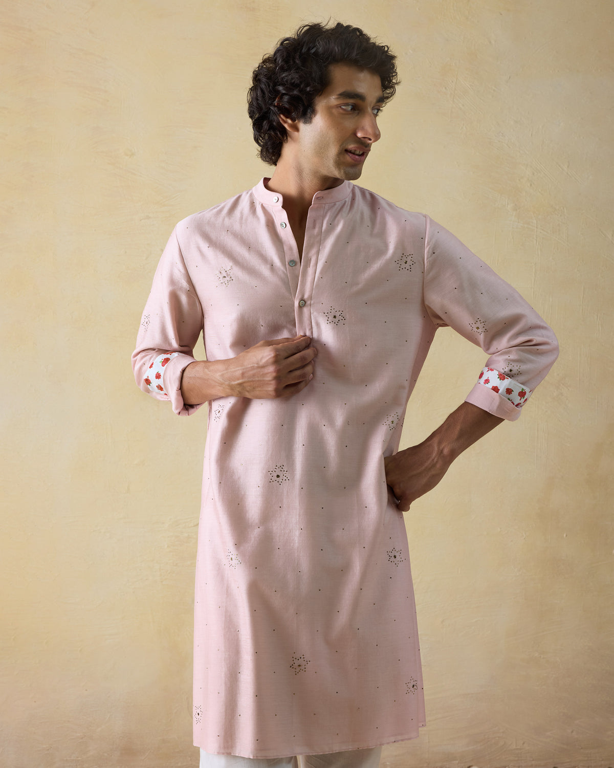 Person wearing a light pink Arham kurta with mukaish stars.