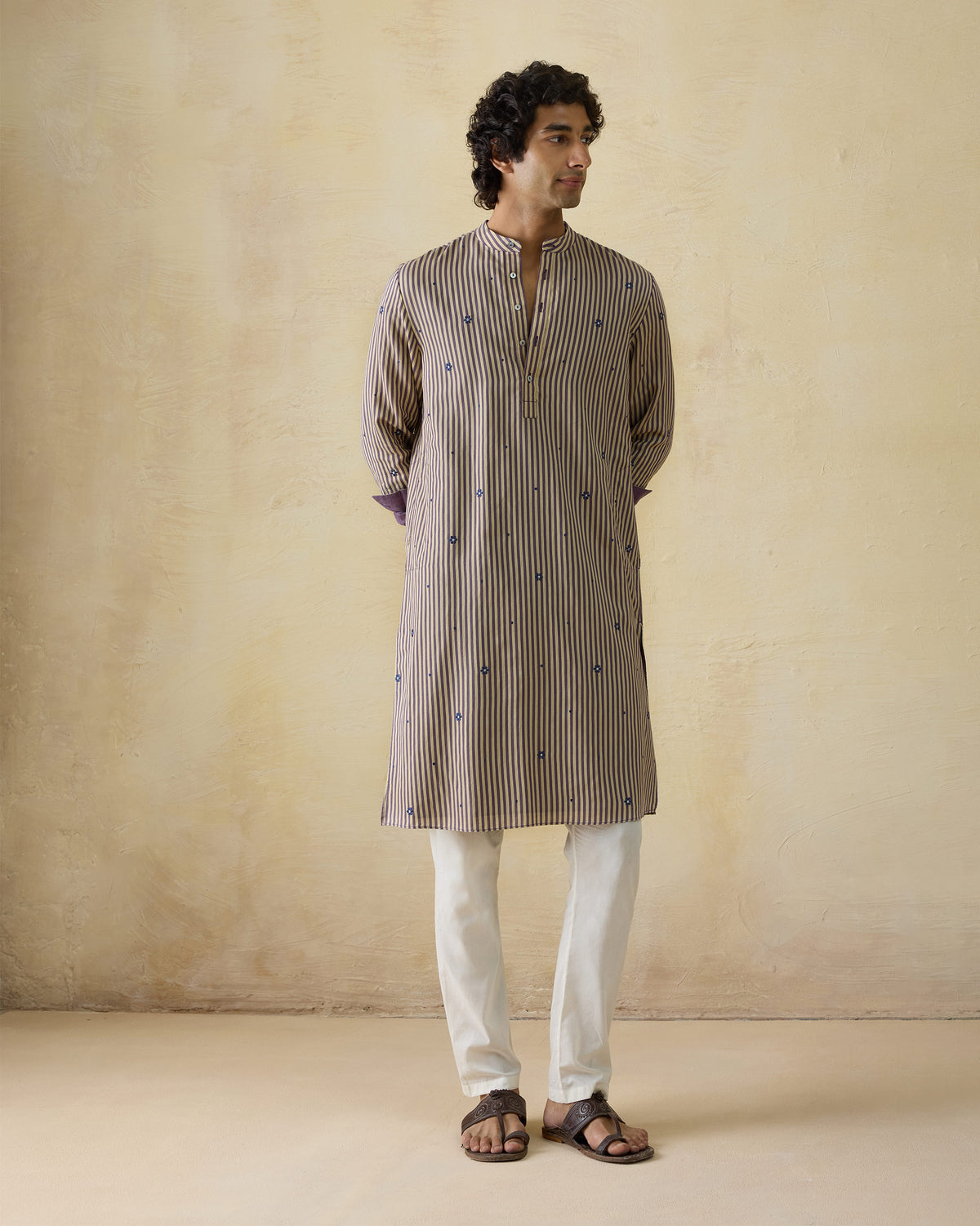Person wearing a beige and navy striped Shaam Kurta with side slits.