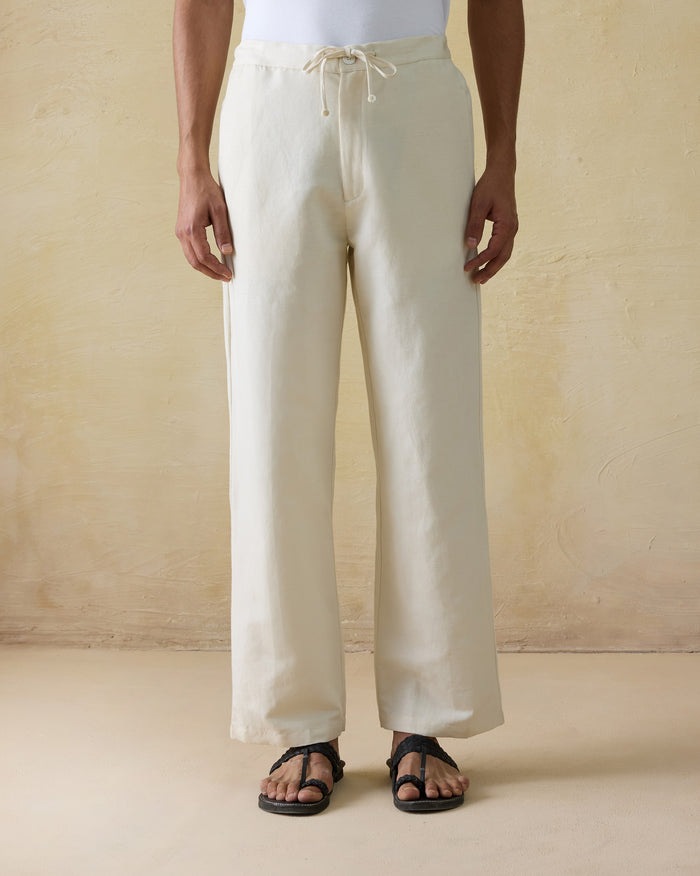 Person wearing ivory Aaram pants with a drawstring waist.