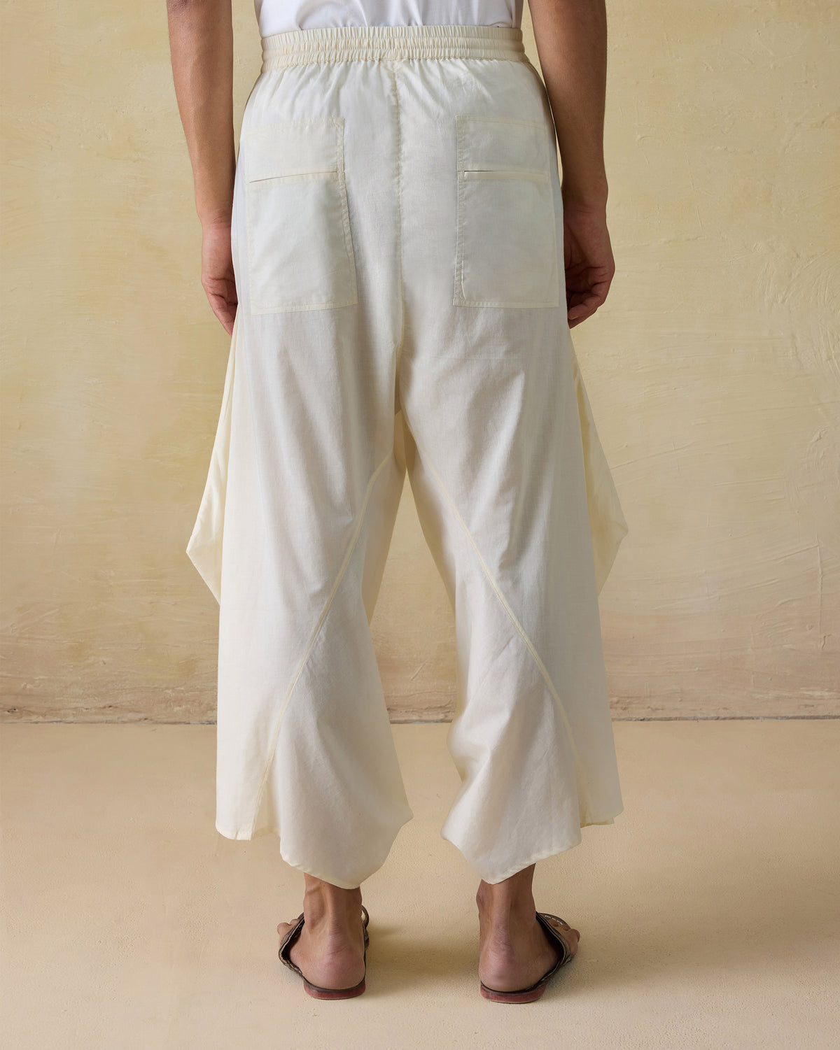 Back of ivory Tahir pants with patch pockets and draped sides.