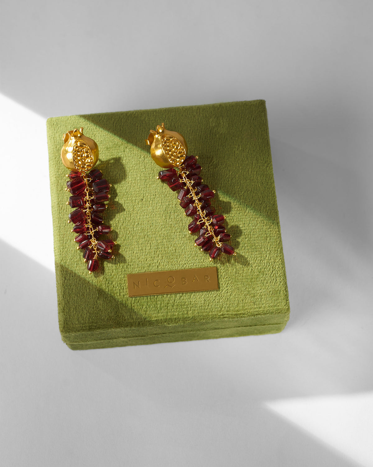 Anaar Bagicha Earring pair displayed on a green velvet box.