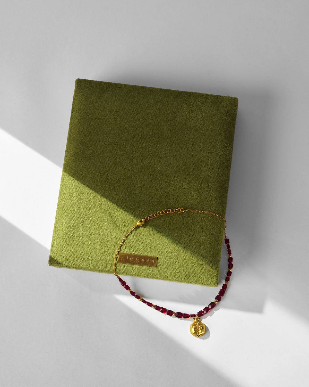 Anar Bagicha necklace with garnet beads on a green Nicobar display block.
