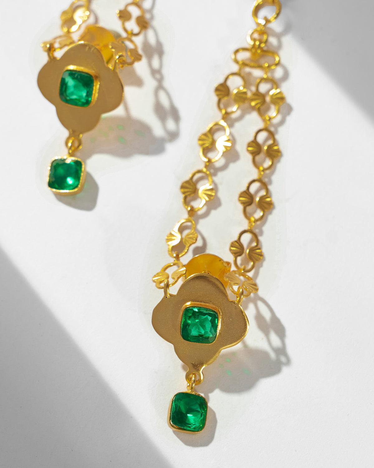 Close-up of gold Clover Kanauti earrings showing the clover links and green stones.