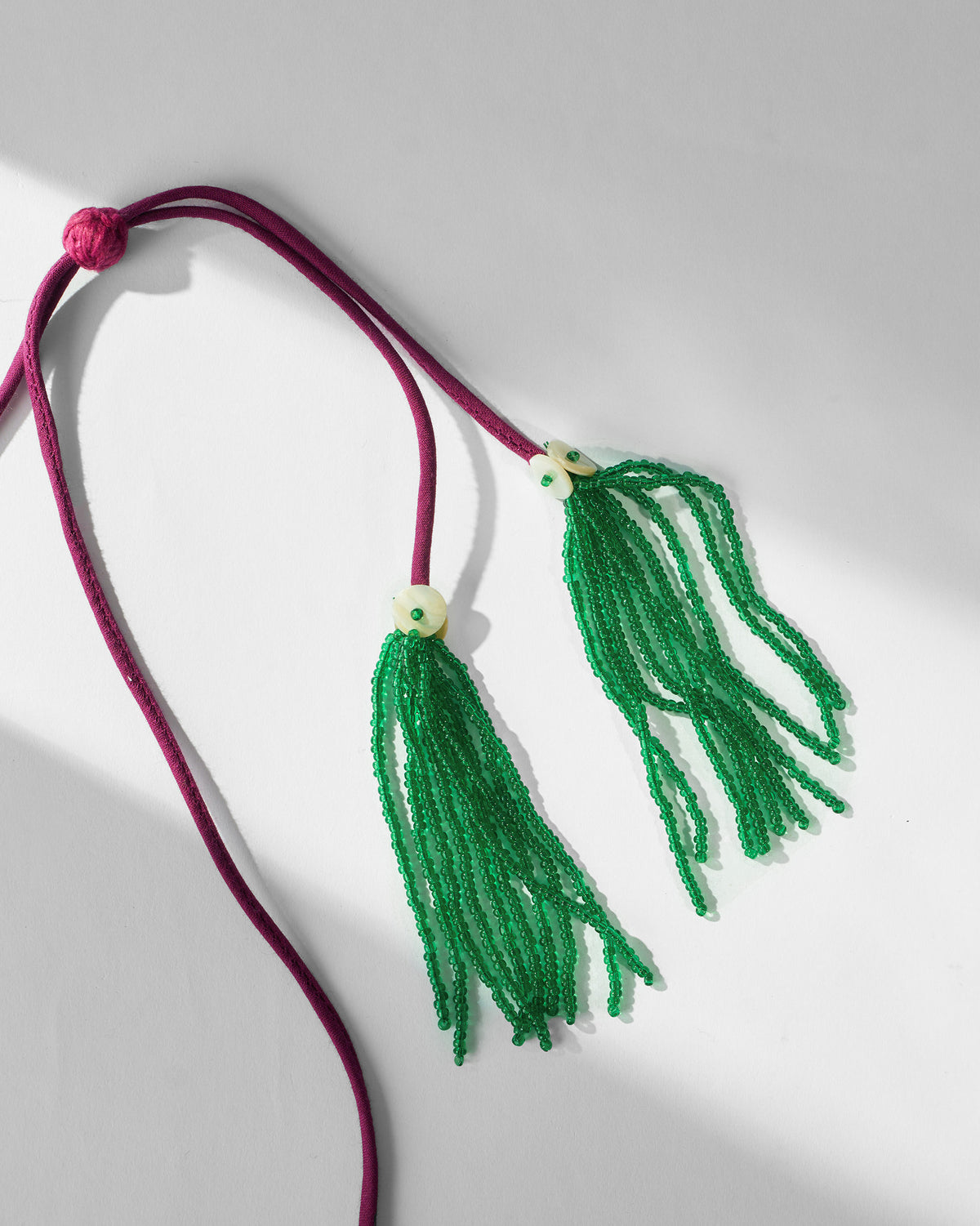 Close-up of green beaded tassels on the Clover necklace cord.