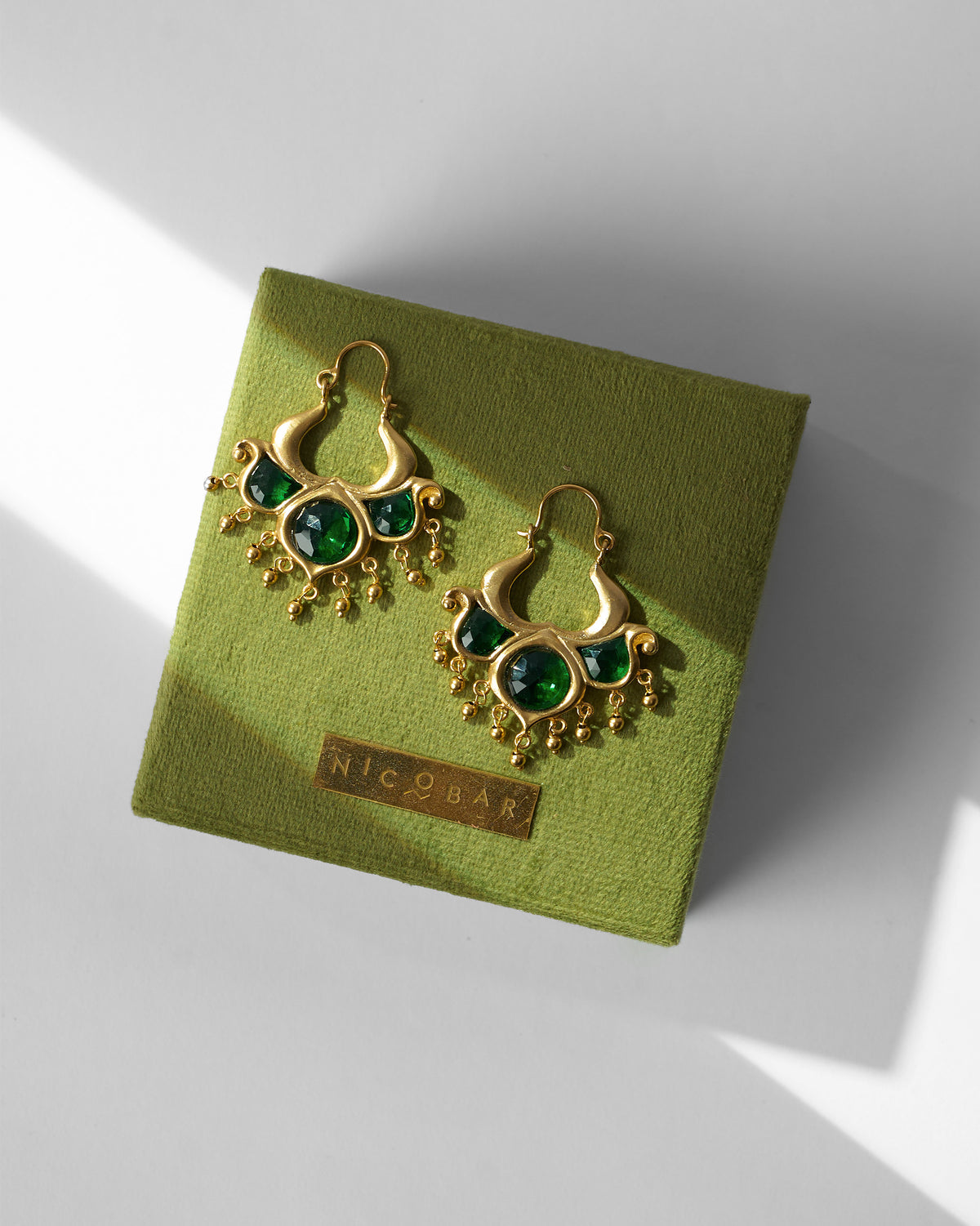 Pair of Darbaar Bali earrings resting on a green gift box.