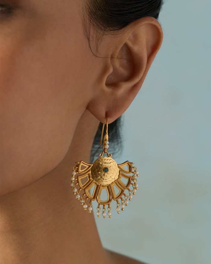 Person wearing gold Marigold Earrings with a fan shape and beaded drops.