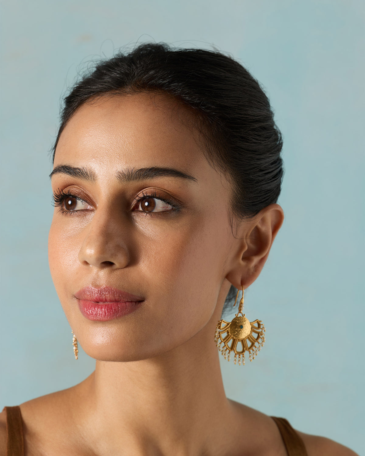 Person wearing gold Marigold Earrings with a fan-shaped drop.
