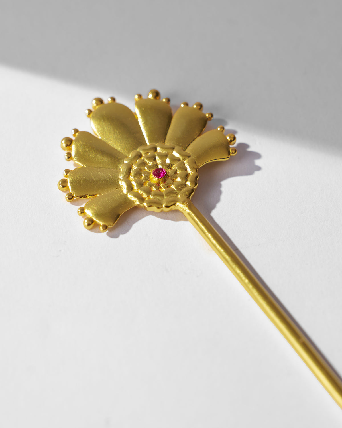Close-up of a gold Mari-Palm hairpin petal fan with pink stone.