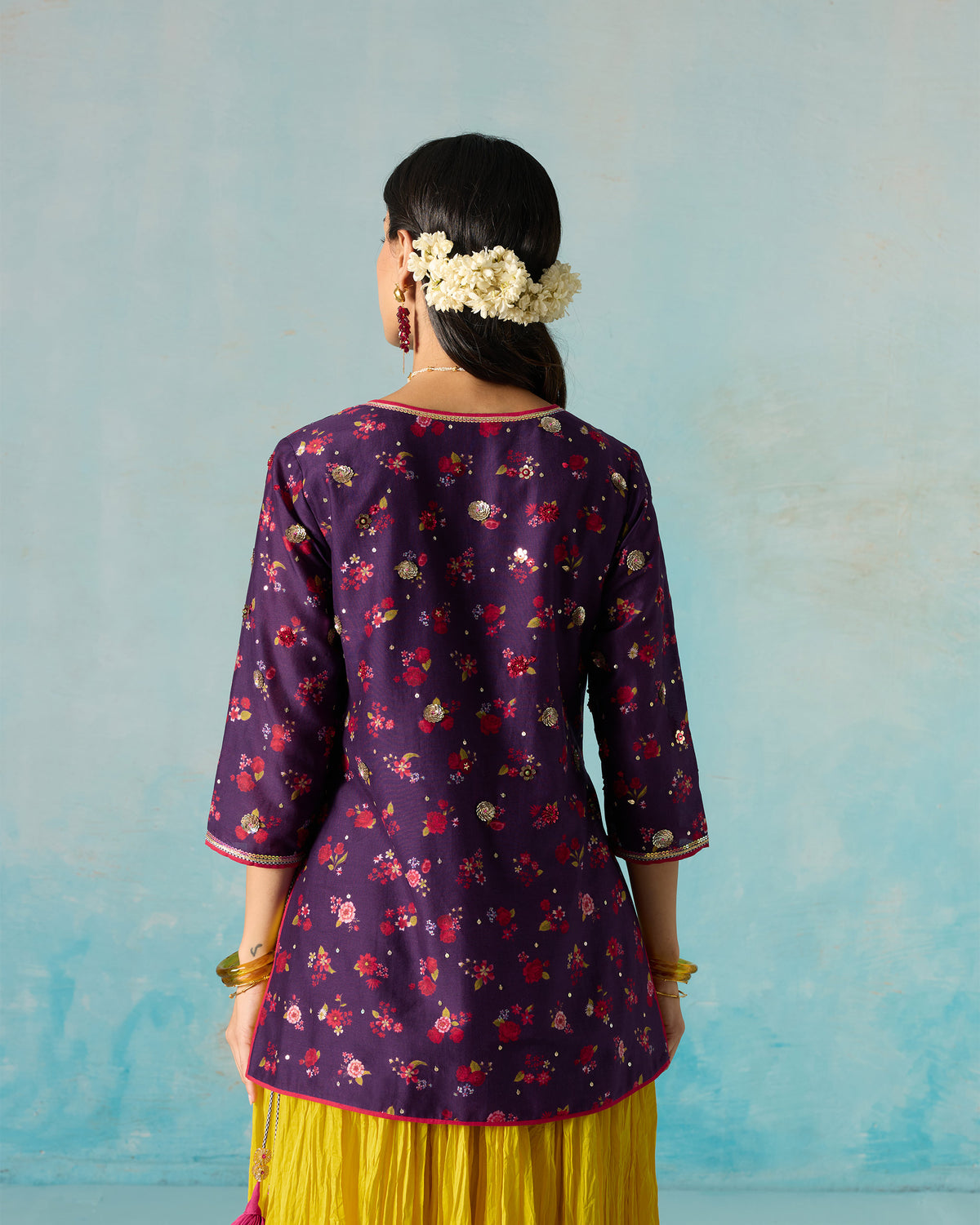 Back of a purple Sehra kurti with a floral print, worn by a person.