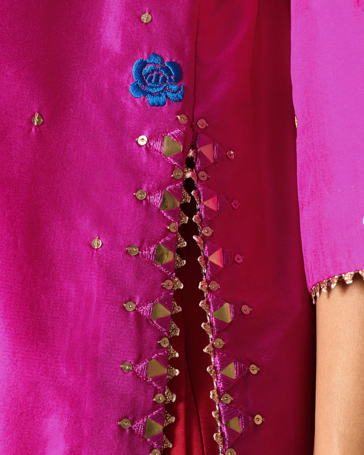 Close-up of mirror and beaded edging along the side slit of a magenta Milni kurta.