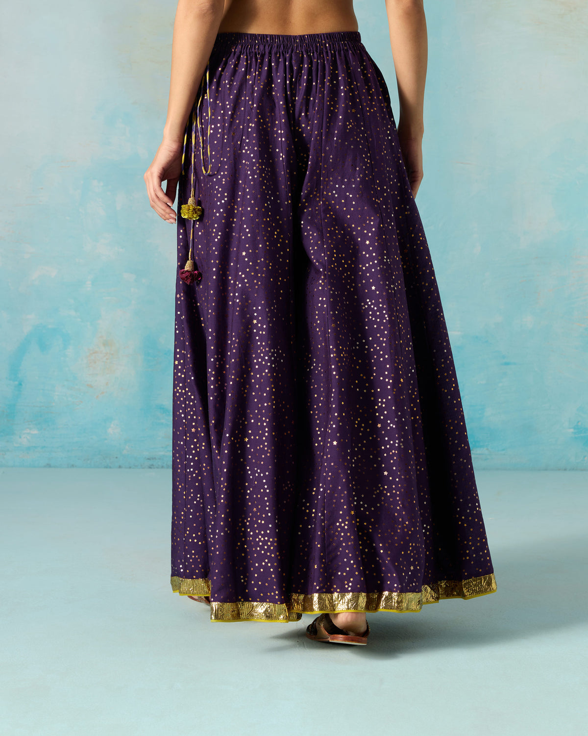 Back of a purple Sagan sharara with gold foil dots and a gold hem border.