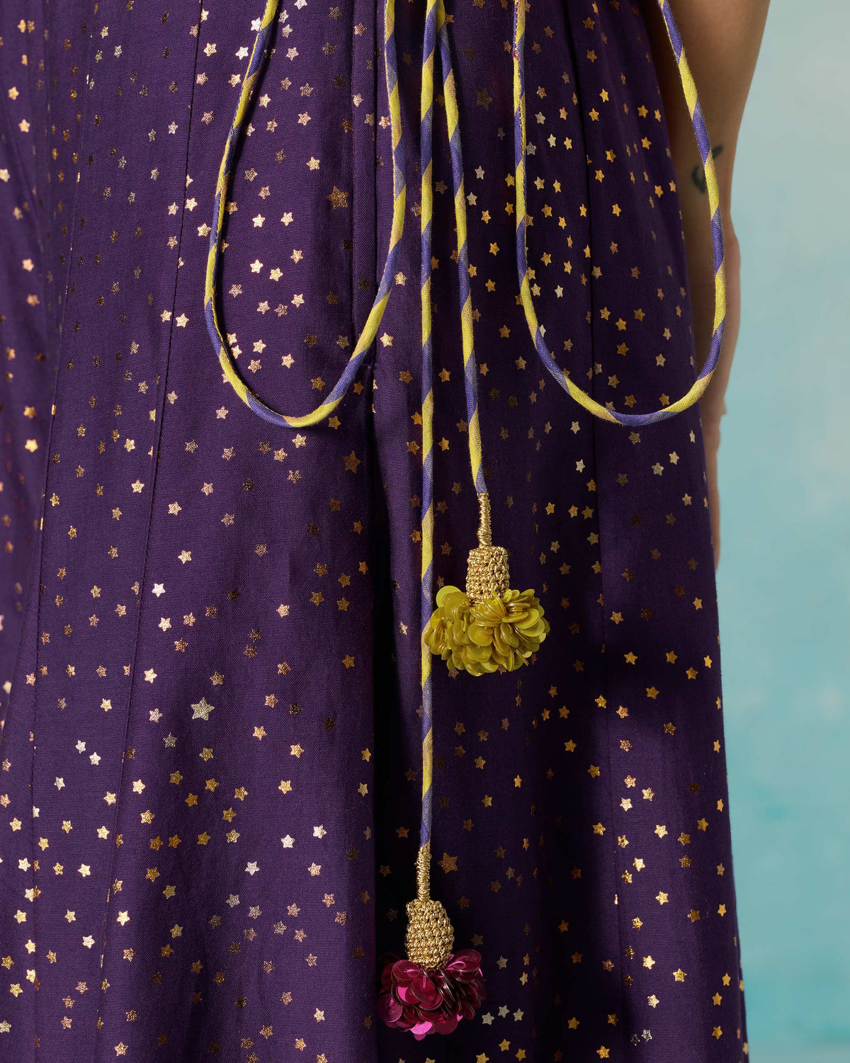 Close-up of gold foil stars and colourful tassels on a purple Sagan sharara.
