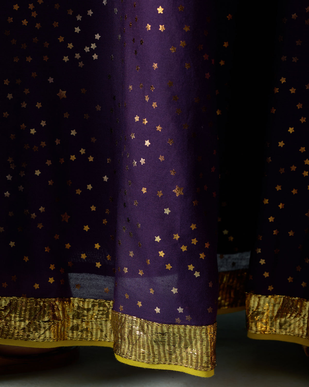 Close-up of the gold hem border and foil stars on a purple Sagan sharara.