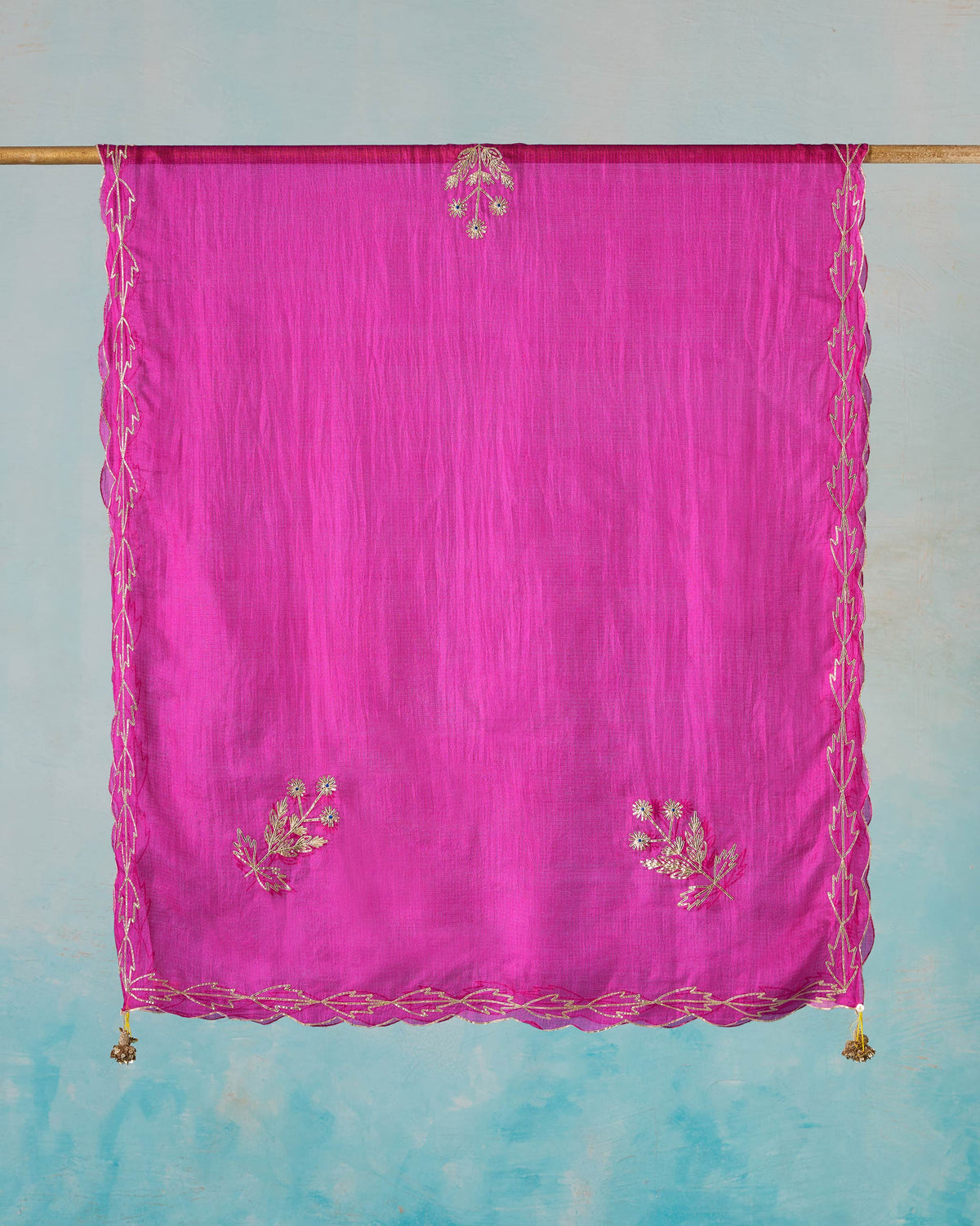 Magenta Ishara dupatta hung flat with gold sprig motifs and a scalloped border.