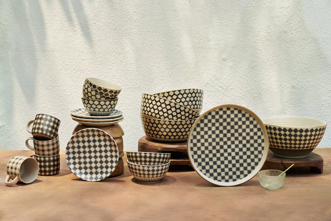 Assorted Fez dinnerware with charcoal diamond patterns on wood risers.