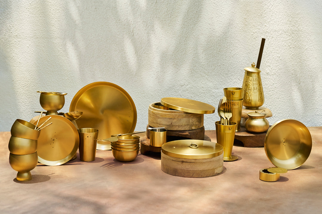 Brass Madhu quarter plate among a styled brass tableware collection.