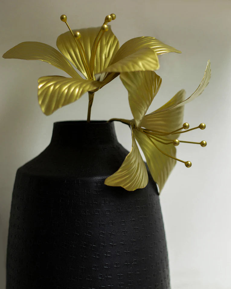 Close-up of gold Kachnar flower accents with ribbed petals in a black vase.