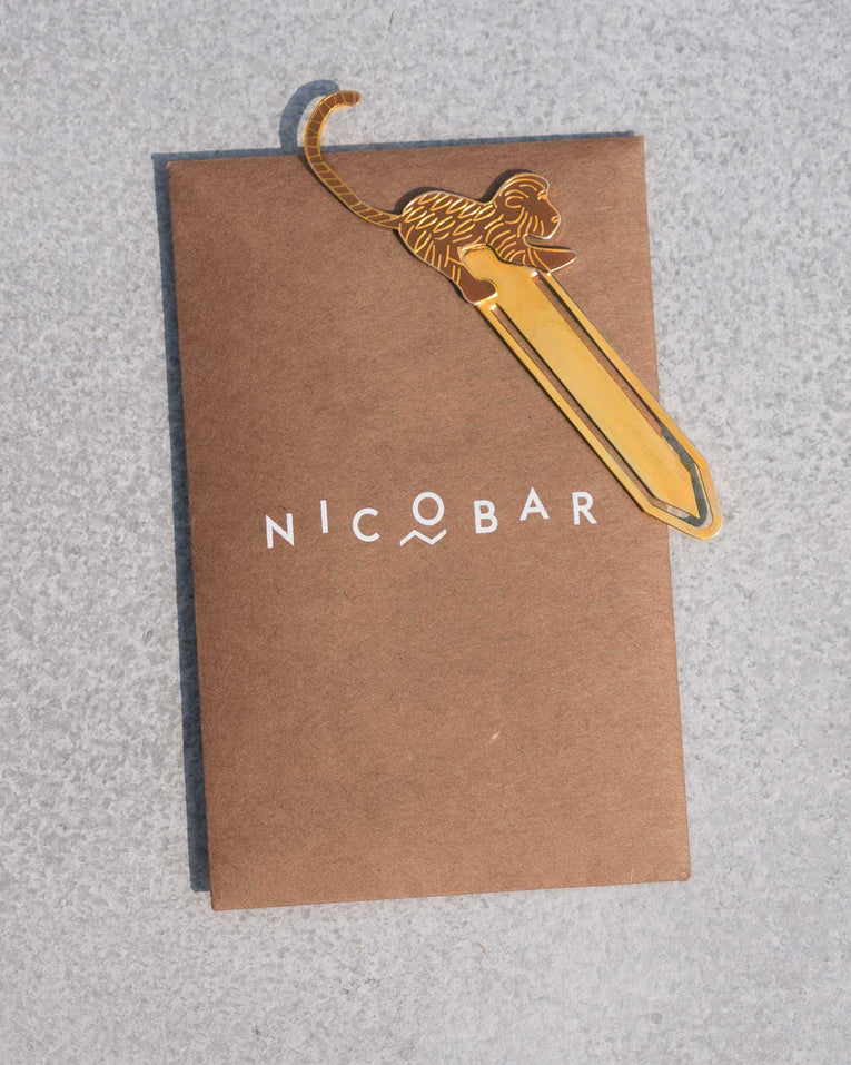 Gold safari monkey bookmark on a Nicobar card.