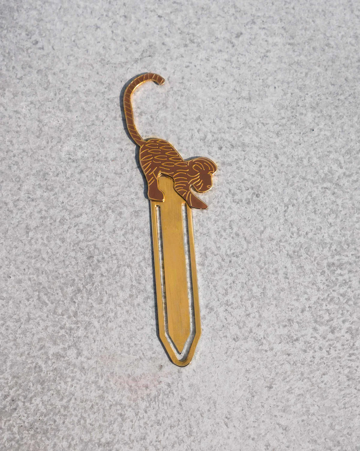 Gold safari monkey bookmark on a grey surface.