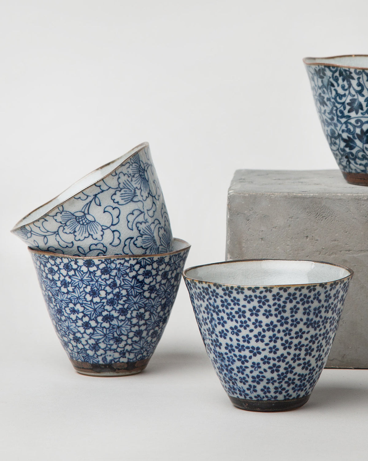 Three Ocha tea cups with blue and white vine and floral prints.