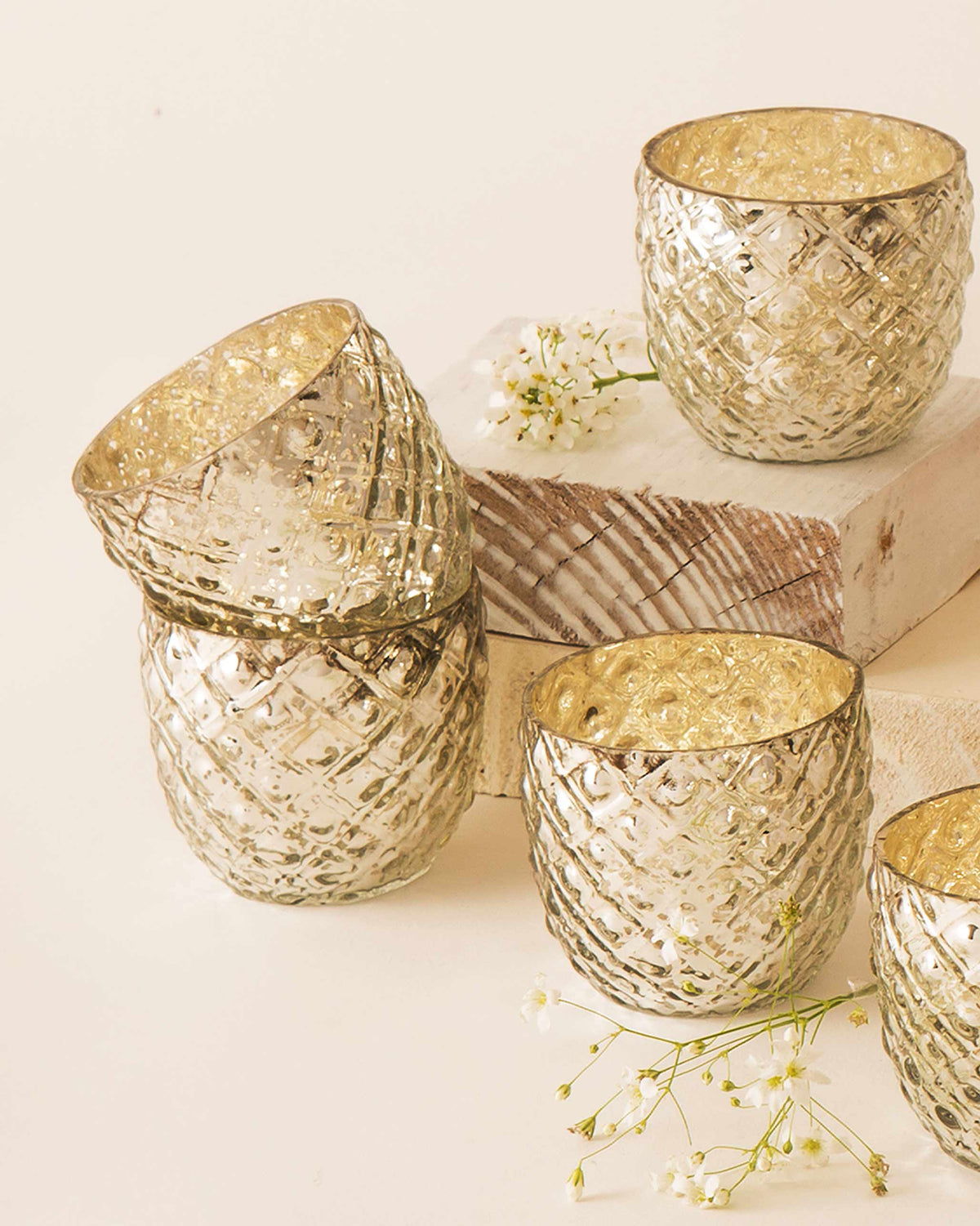 Ziya Votive set arranged on wooden blocks with white sprigs.