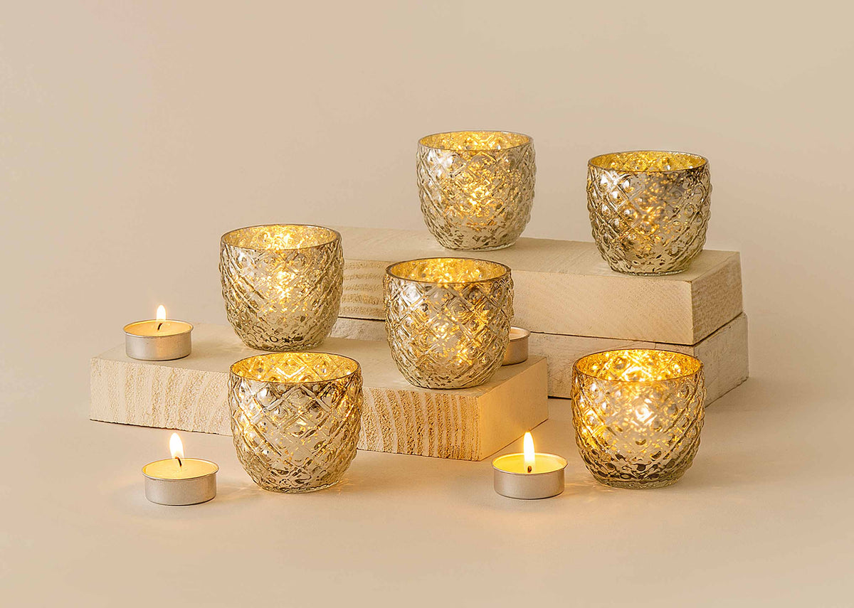 Ziya Votive set lit with tealight candles on wooden blocks.