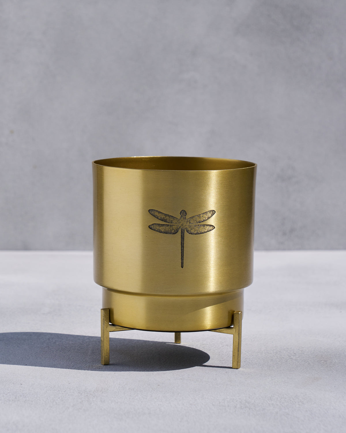 Gold Dune planter on a tripod stand with an etched dragonfly.