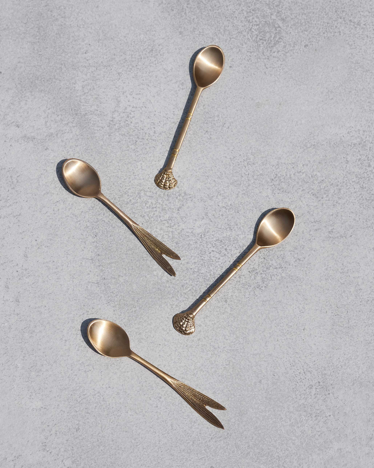 Four Bahr coffee spoons scattered on a grey surface.