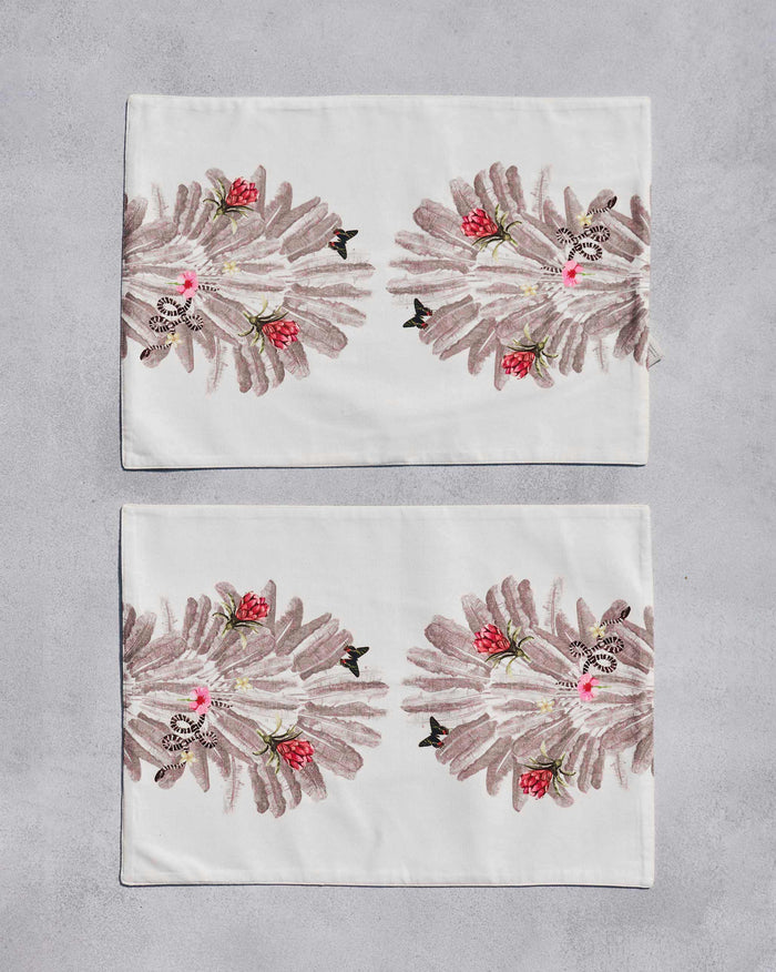 Overhead view of two Ravenala Placemats with a red flower and leaf print.