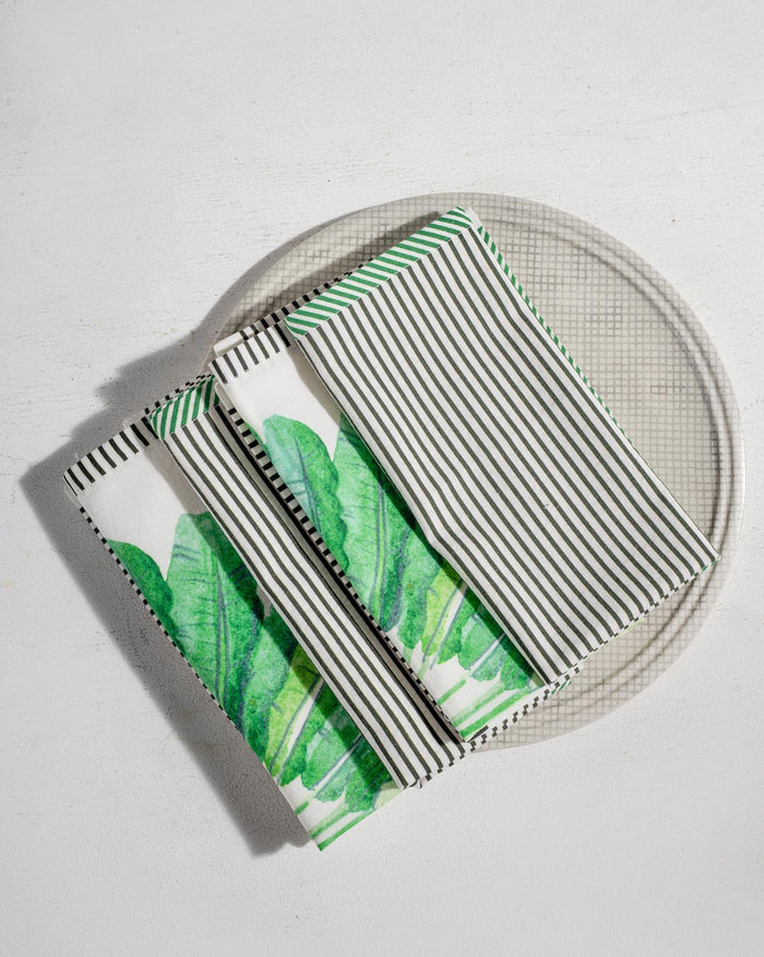 Set of Ravenala dinner napkins with palm prints and black stripes.