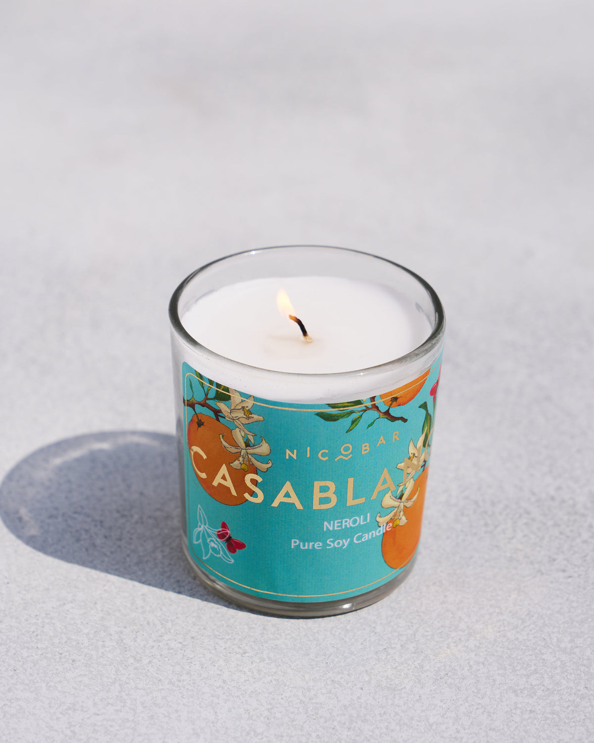 The lit Casablanca Jar Candle with its turquoise label.