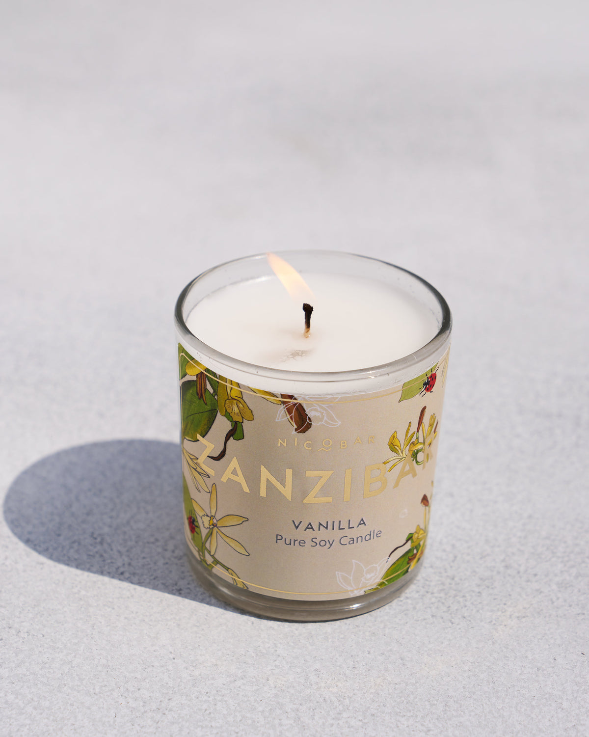 The lit Zanzibar Jar Candle with its vanilla label.