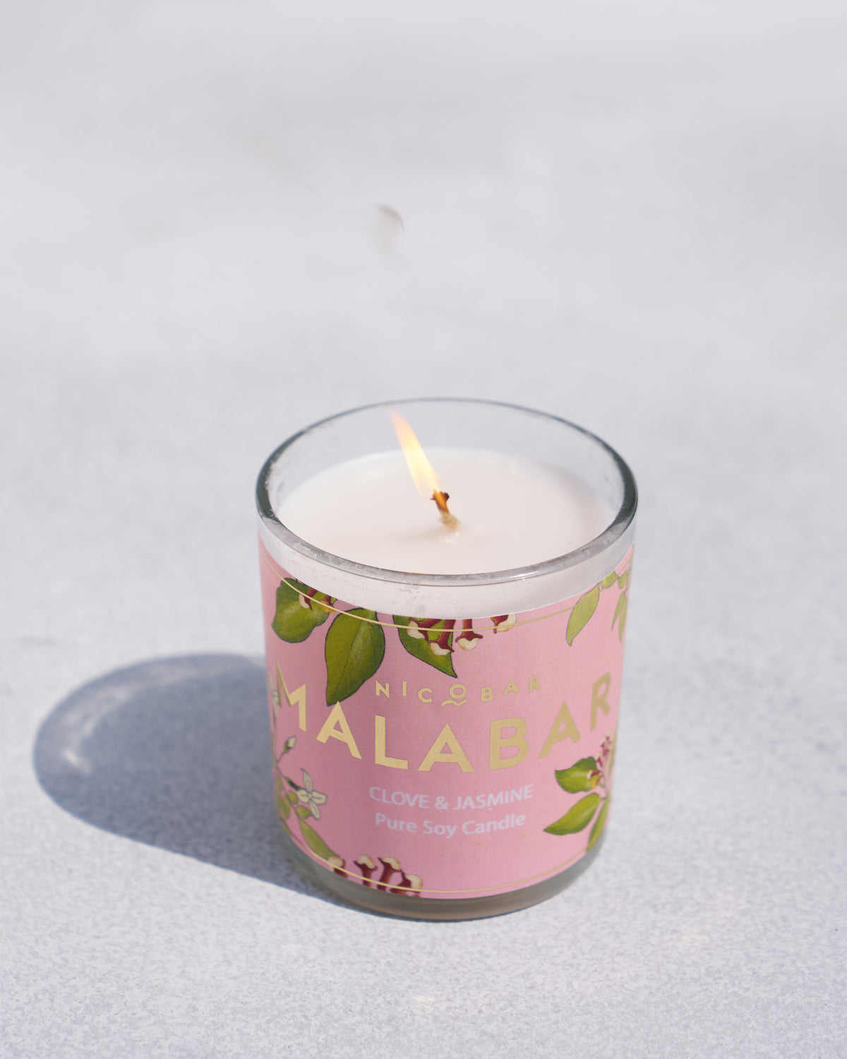 The lit Malabar Jar Candle with its pink label.