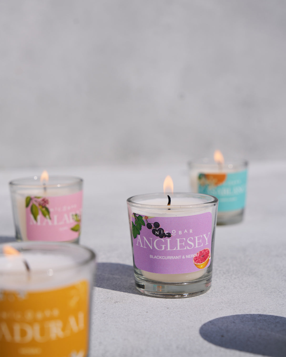 Lit Nicobar jar candles including Anglesey with a purple berry label.