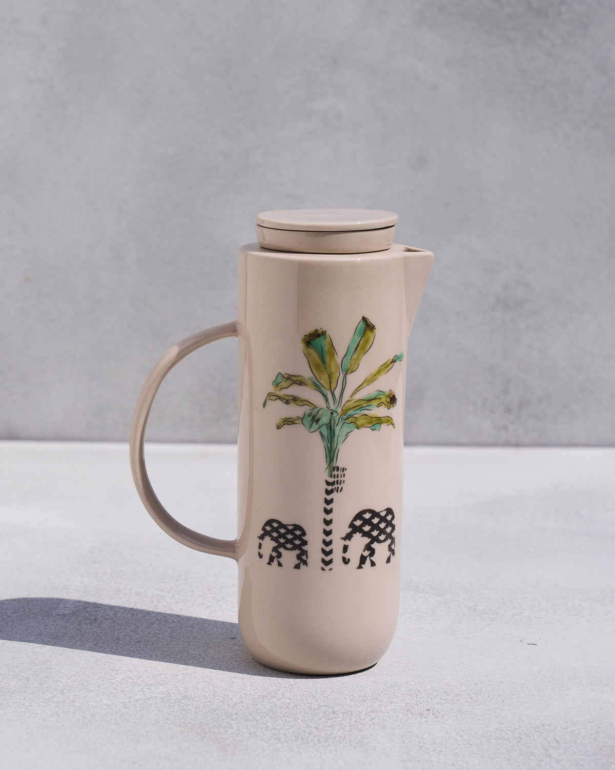 Beige Ele carafe with a palm tree and two elephants on the front.