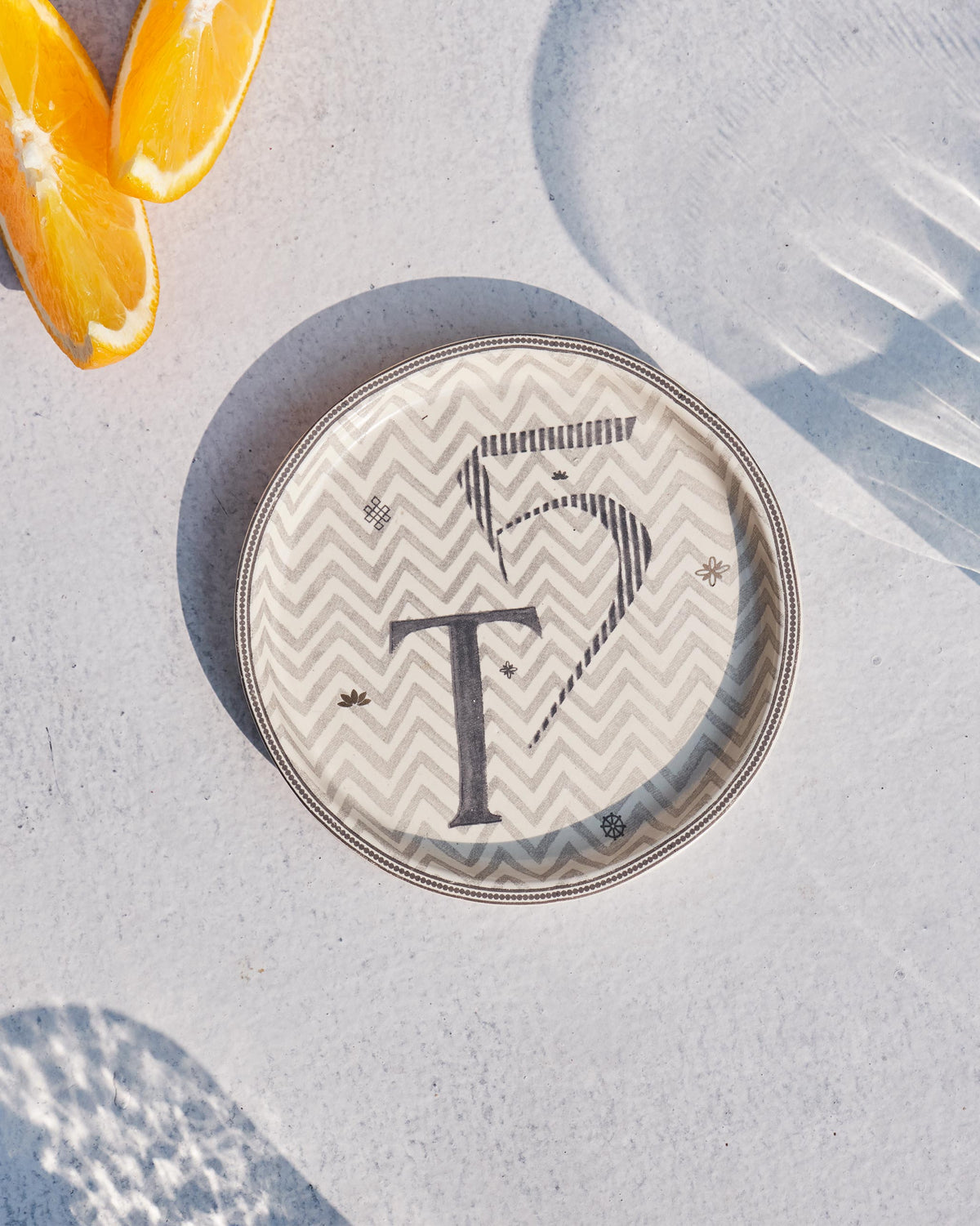 Akshar Coaster - T laid flat, showing the grey T glyph on a chevron pattern.