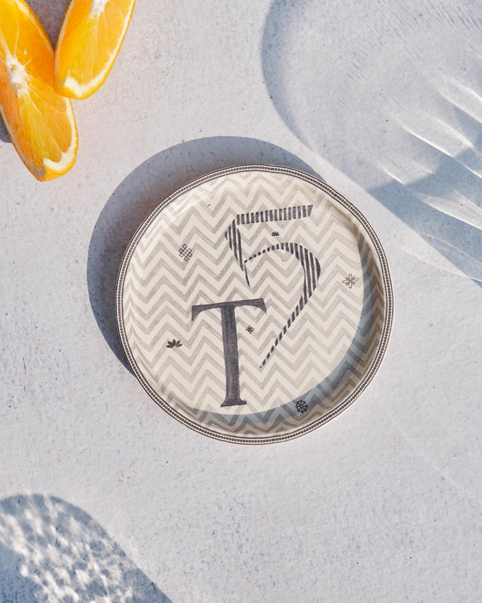 Akshar Coaster - T laid flat, showing the grey T glyph on a chevron pattern.