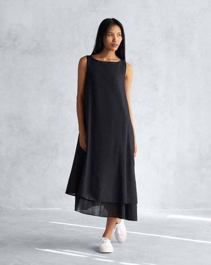 Person wearing a sleeveless black Double layer dress with a layered hem.