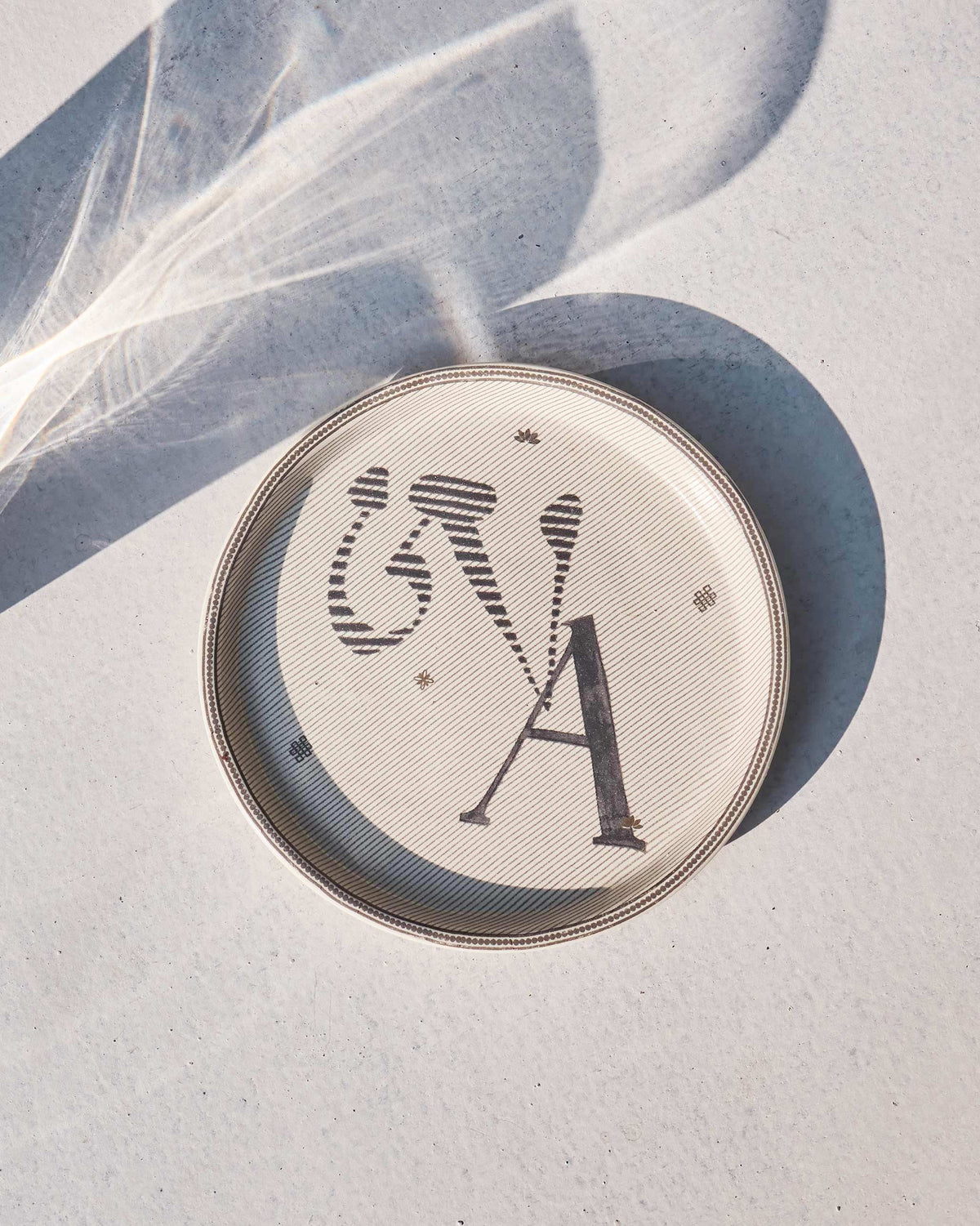 The Akshar Coaster with a charcoal A.