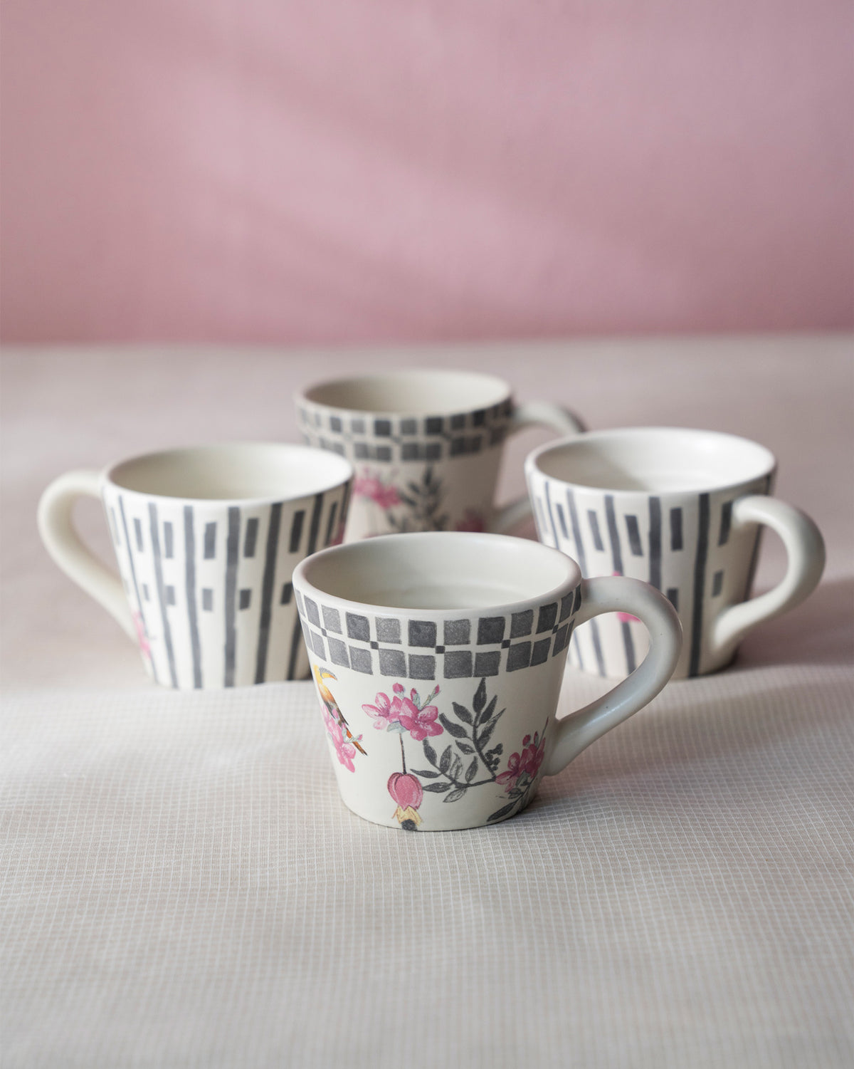 Four Nectar espresso mugs in floral bird and grey dash prints arranged together.