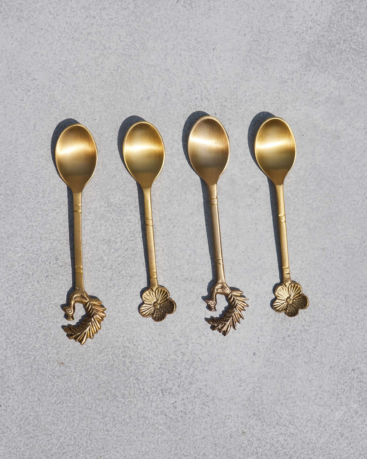 Set of four brass Mizo coffee spoons with peacock and flower tips.