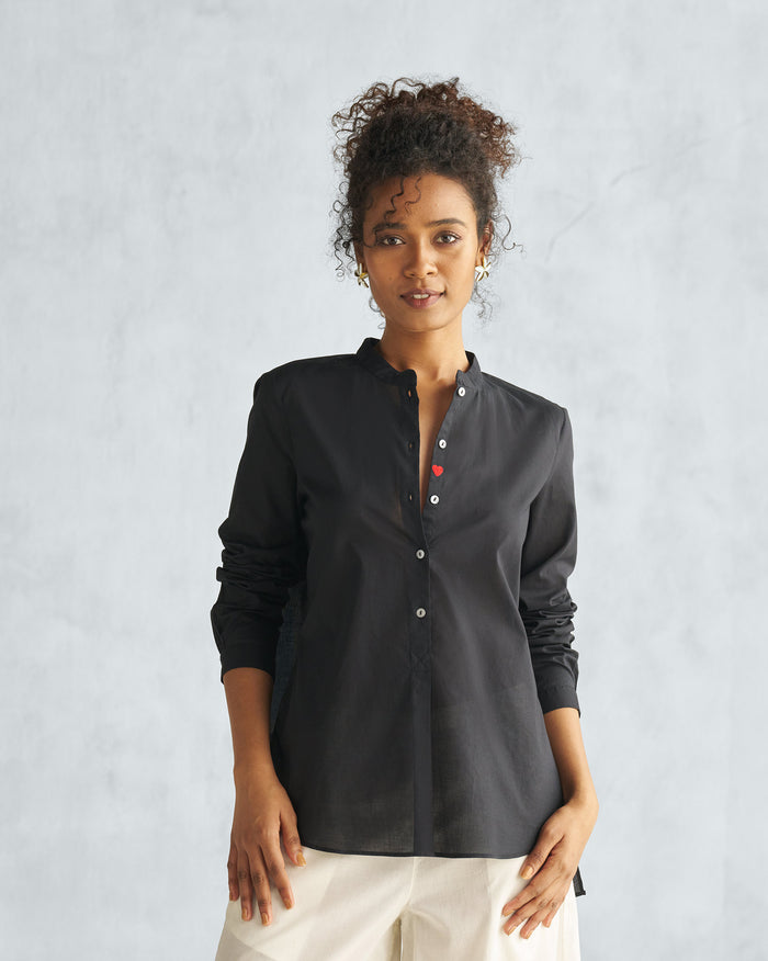 Person wearing a black mandarin collar top with a red heart.